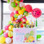 Colorful balloon arch with fruit-themed decorations and a birthday sign.