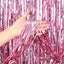 Pink metallic curtain backdrop with a hand holding it