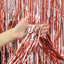 Hand holding rose gold tinsel curtain backdrop against a rose gold tinsel curtain