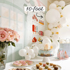 Decorated birthday party setup with balloons, cake, and flowers in a room.