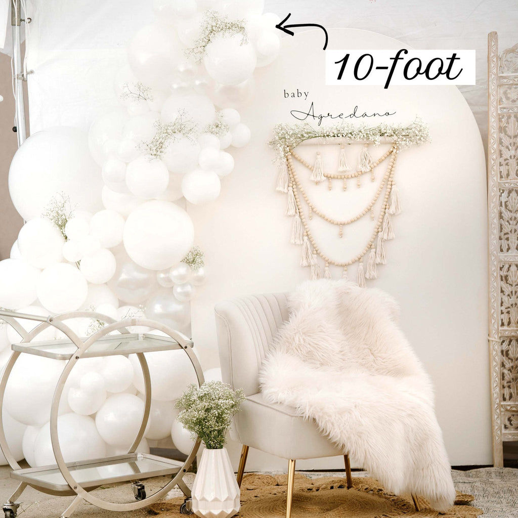 Decorative setup with balloons, a chair, and a decorative wall hanging in a room.