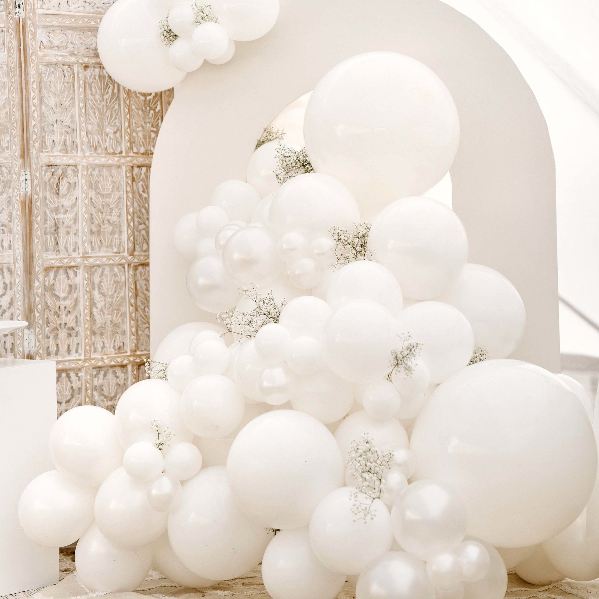 White balloon arch with decorative elements in a room setting Main image
