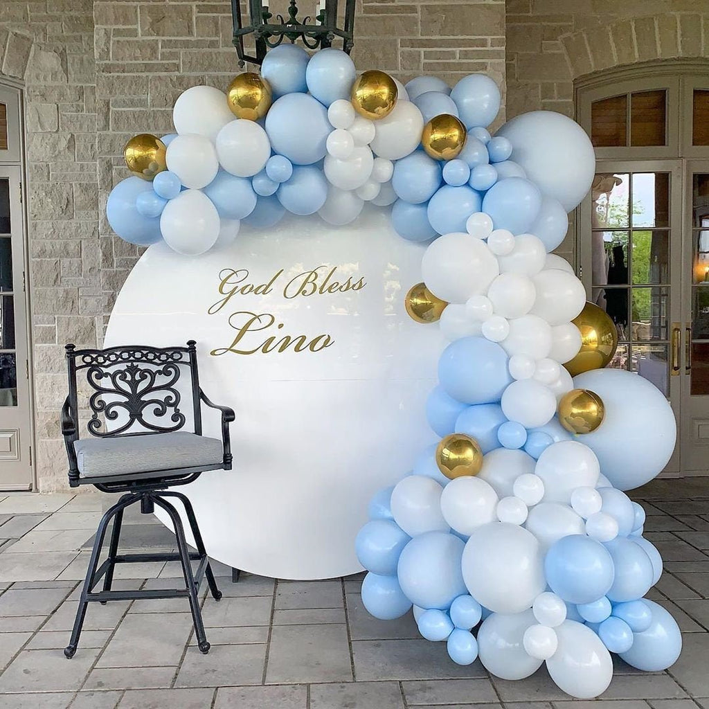 Balloon arch with blue, white, and gold balloons in front of a building entrance.