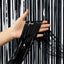 Hand holding black tinsel against a black and white striped background