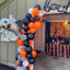 Halloween-themed balloon arch with a decorated garage door in the background