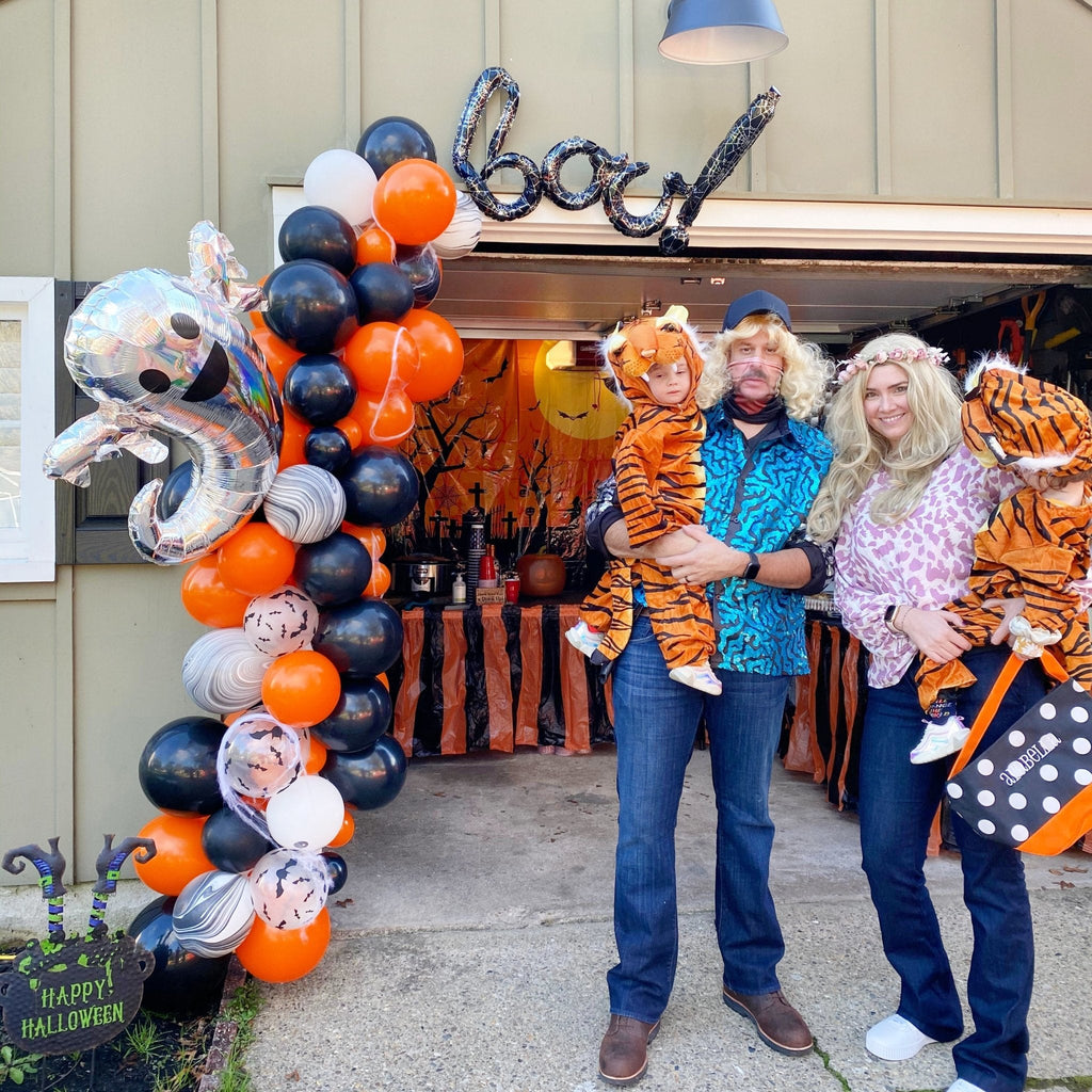 Family with children in tiger costumes standing in front of a decorated truck for Halloween.