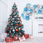 Decorated Christmas tree with ornaments and presents in a room with a balloon arch.