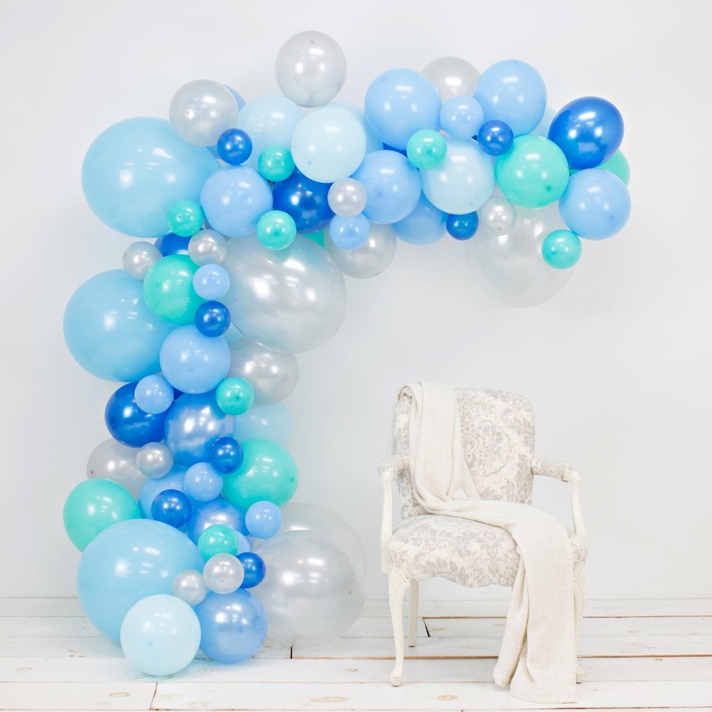 Balloon arch with blue, green, and white balloons against a white wall. Main image