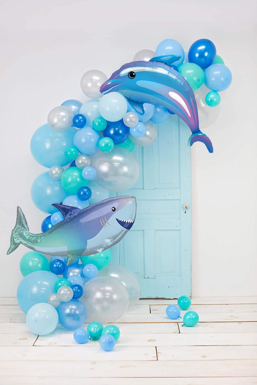 Decorative balloon arch with dolphin and shark balloons against a light blue door.