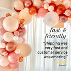 Balloon arch with pink, orange, and white balloons against a white curtain background.