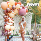 Woman standing next to a large balloon arch on a deck with decorative plants and furniture.