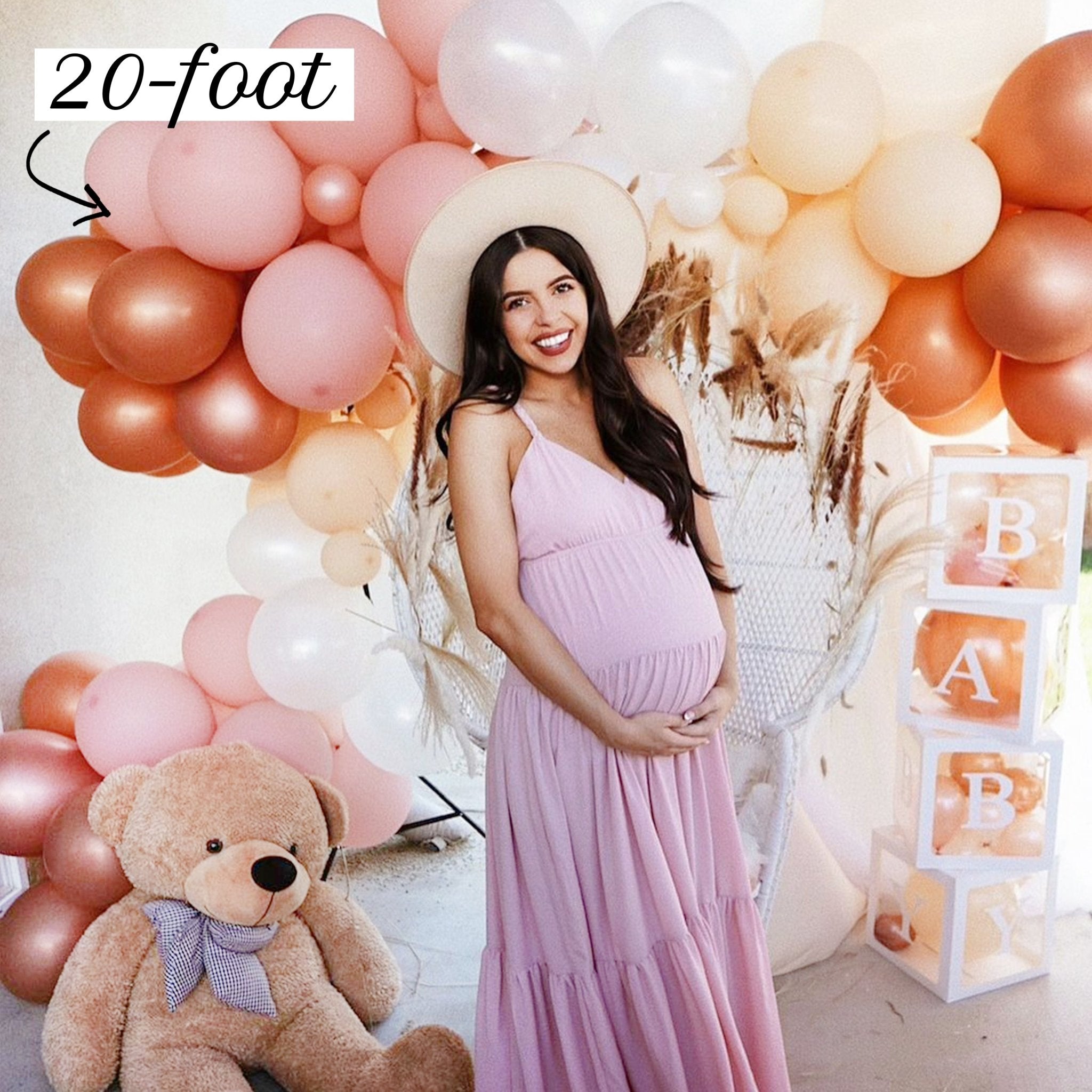 Pregnant woman in a pink dress surrounded by balloons and a teddy bear, with '20-foot' text.