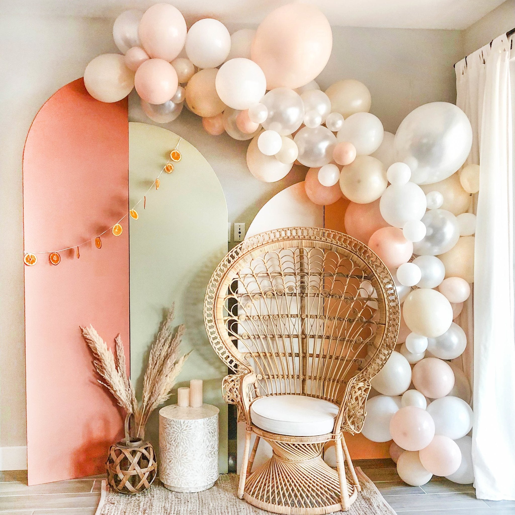 Decorative Balloon Garland with a wicker chair and pink wall in a room.