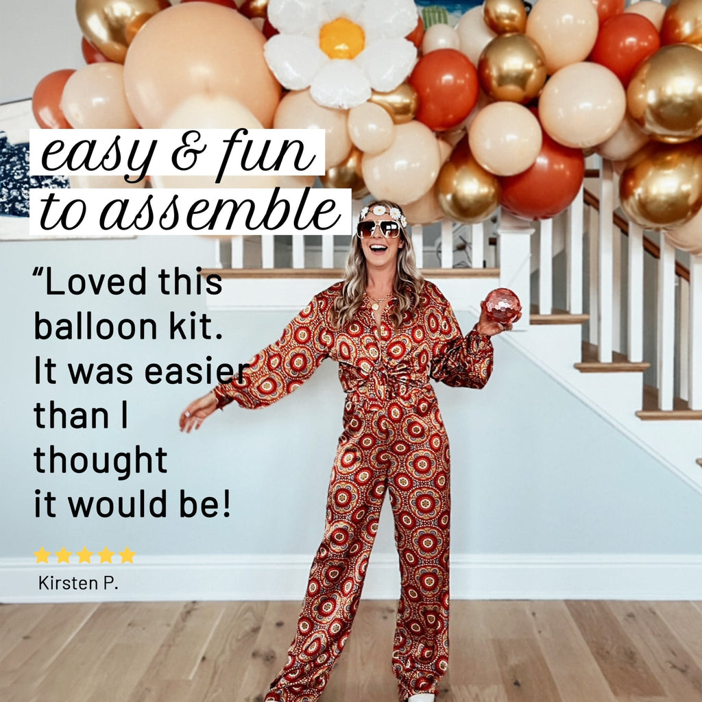Woman in a patterned jumpsuit standing in front of a balloon arch with text about the balloon kit.