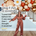 Woman in a patterned jumpsuit standing in front of a balloon arch with text about the balloon kit.