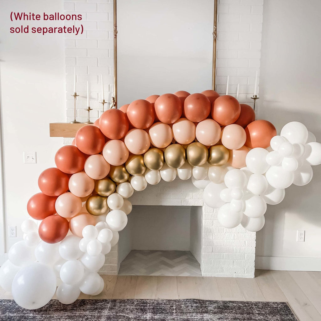Balloon arch with red, gold, and white balloons in a room setting.