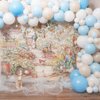 Balloon arch with blue and white balloons in front of a Peter Rabbit Photo illustration Backdrop