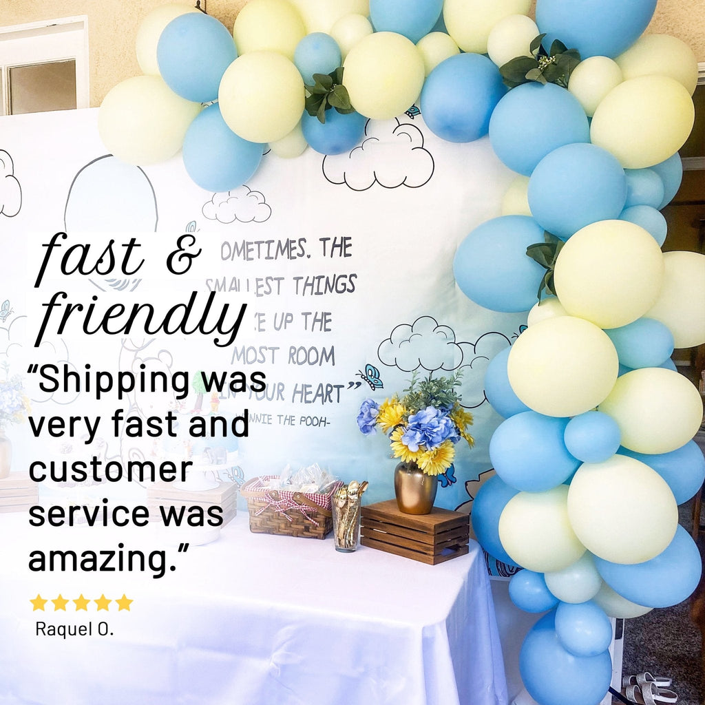 Balloon arch with blue and yellow balloons, flowers, and a sign about fast shipping and customer service.