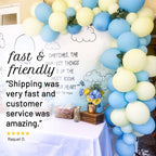 Balloon arch with blue and yellow balloons, flowers, and a sign about fast shipping and customer service.