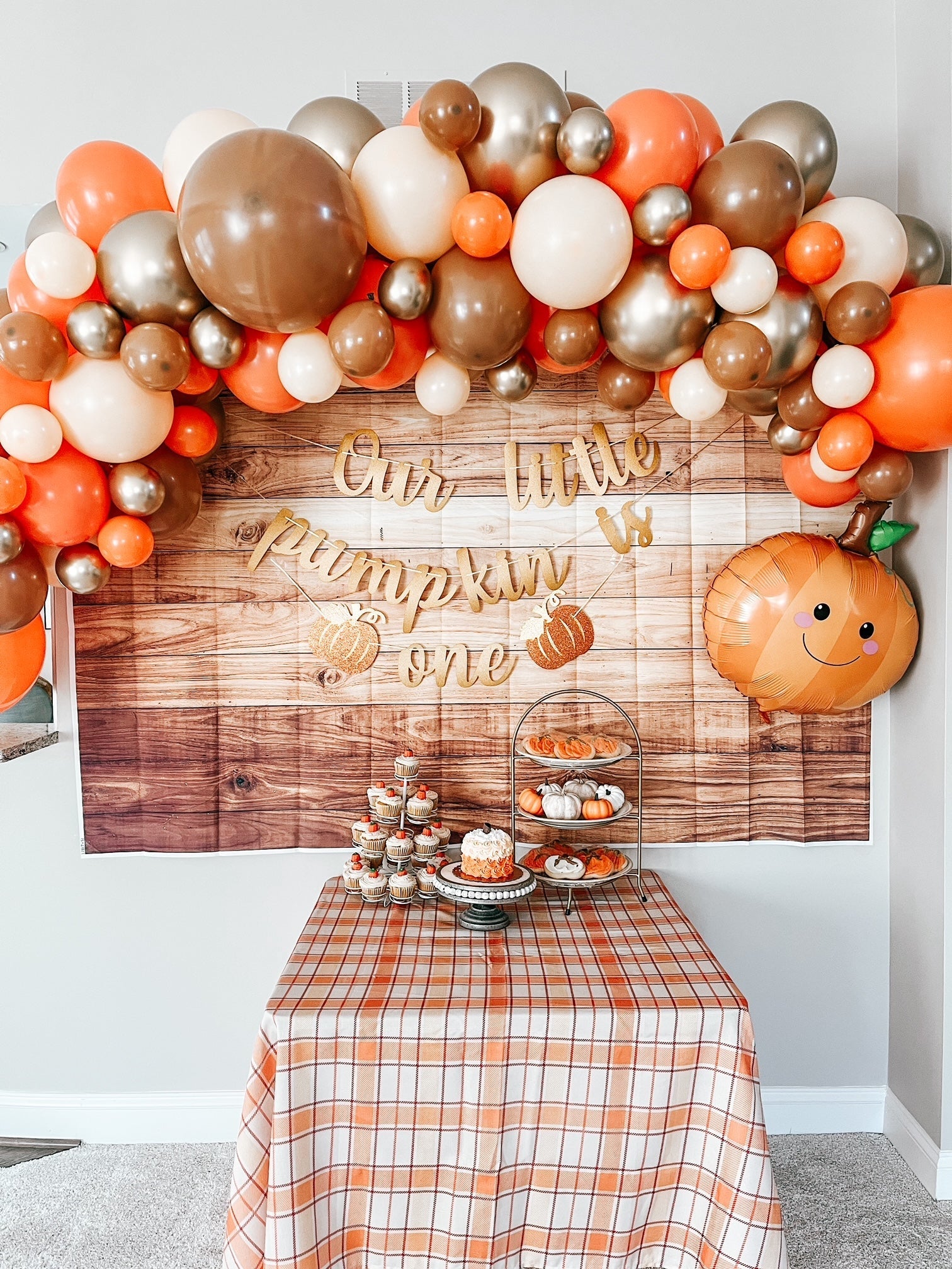 Decorative setup with balloons, a wooden backdrop, and a table with treats.