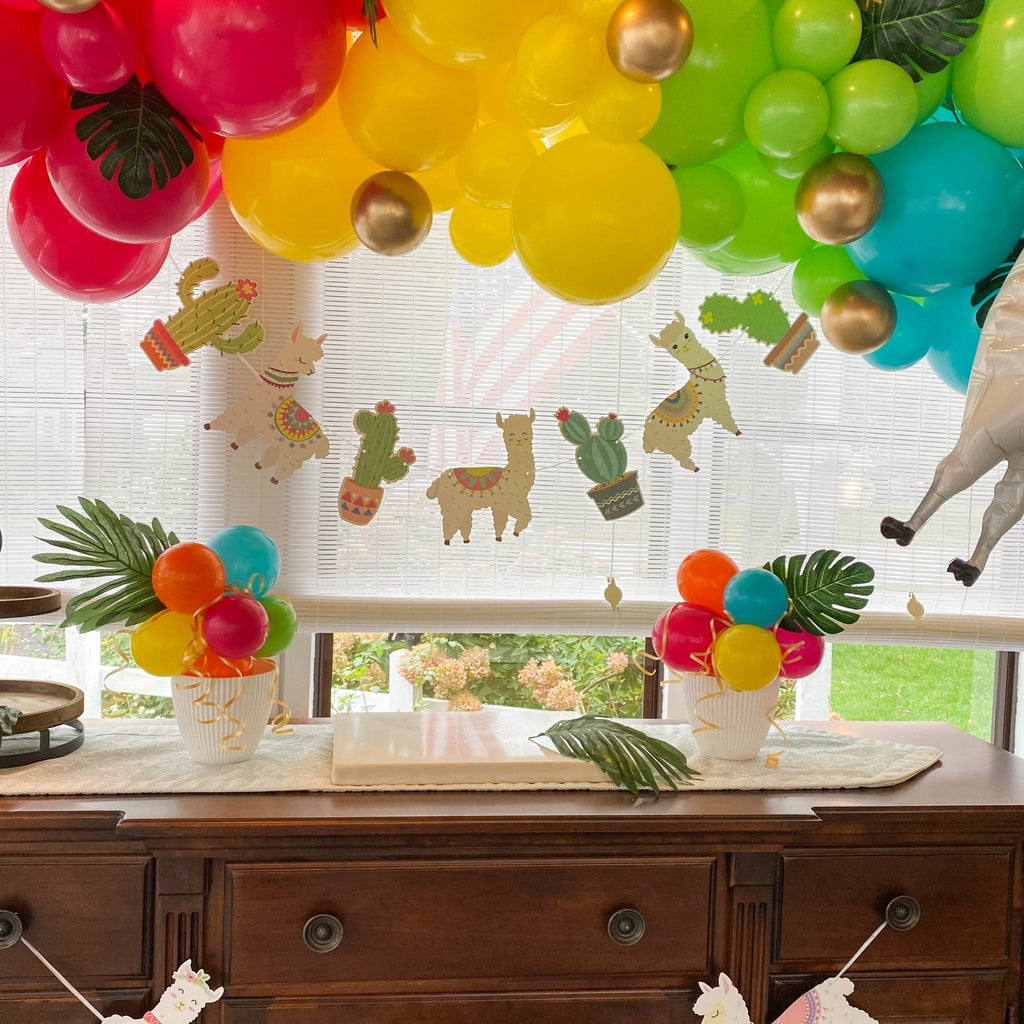 Decorative setup with colorful balloons, plants, and animal-themed decorations on a window.