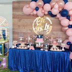 Baby shower dessert table with pink and blue balloons, 'Oh Baby' sign, and various pastries.
