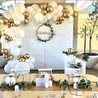 Decorative setup with balloons, table settings, and a wreath on a textured wall.