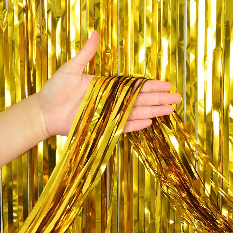 Gold metallic fringe tinsel curtain backdrop being held against a gold fringe curtain background Main image