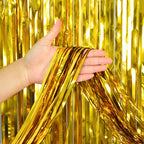 Gold metallic fringe tinsel curtain backdrop being held against a gold fringe curtain background