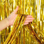 Gold metallic fringe tinsel curtain backdrop being held against a gold fringe curtain background