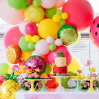 Colorful balloon arch with fruit-themed decorations including balloons shaped like fruits and a cake.
