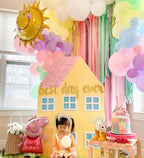 Colorful birthday party setup with balloons, a house-shaped prop, and a child.