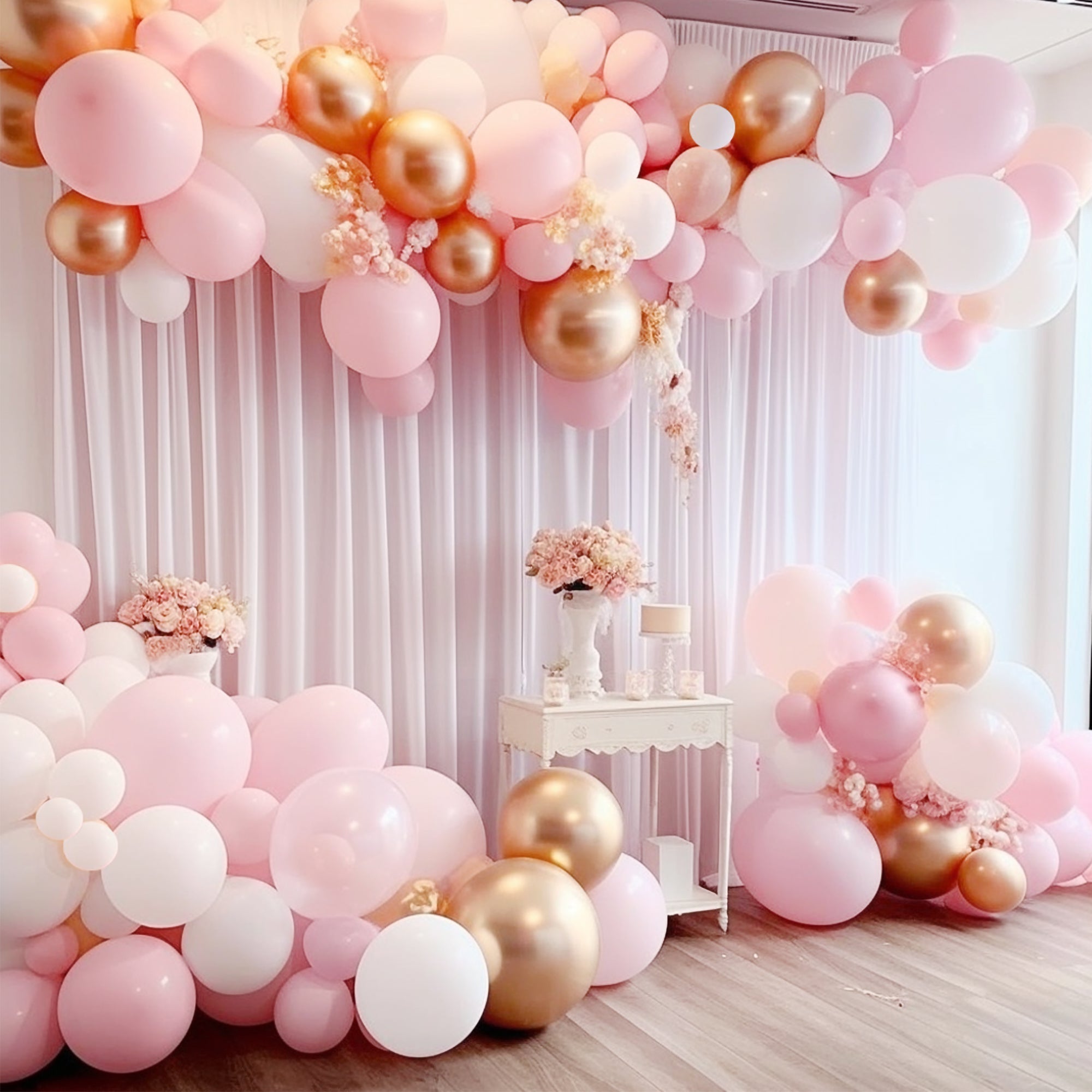 Balloon arch with pink, gold, and white balloons in a room setting. Main image