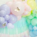 Pastel-colored balloon arch with tassels and butterfly decorations.