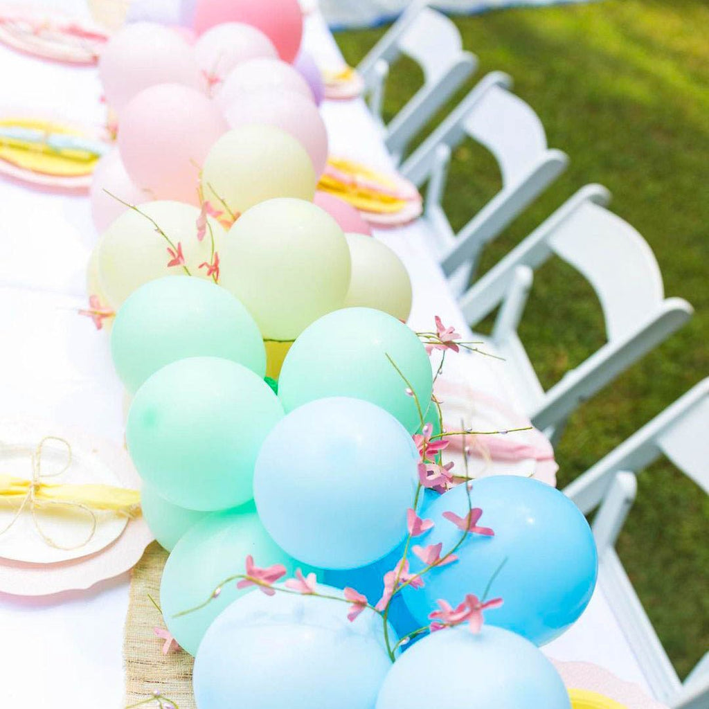 Decorative arrangement of pastel balloons and ribbons on a chair with outdoor setting.
