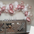 Balloon arch with pink and white balloons above a wooden console table.
