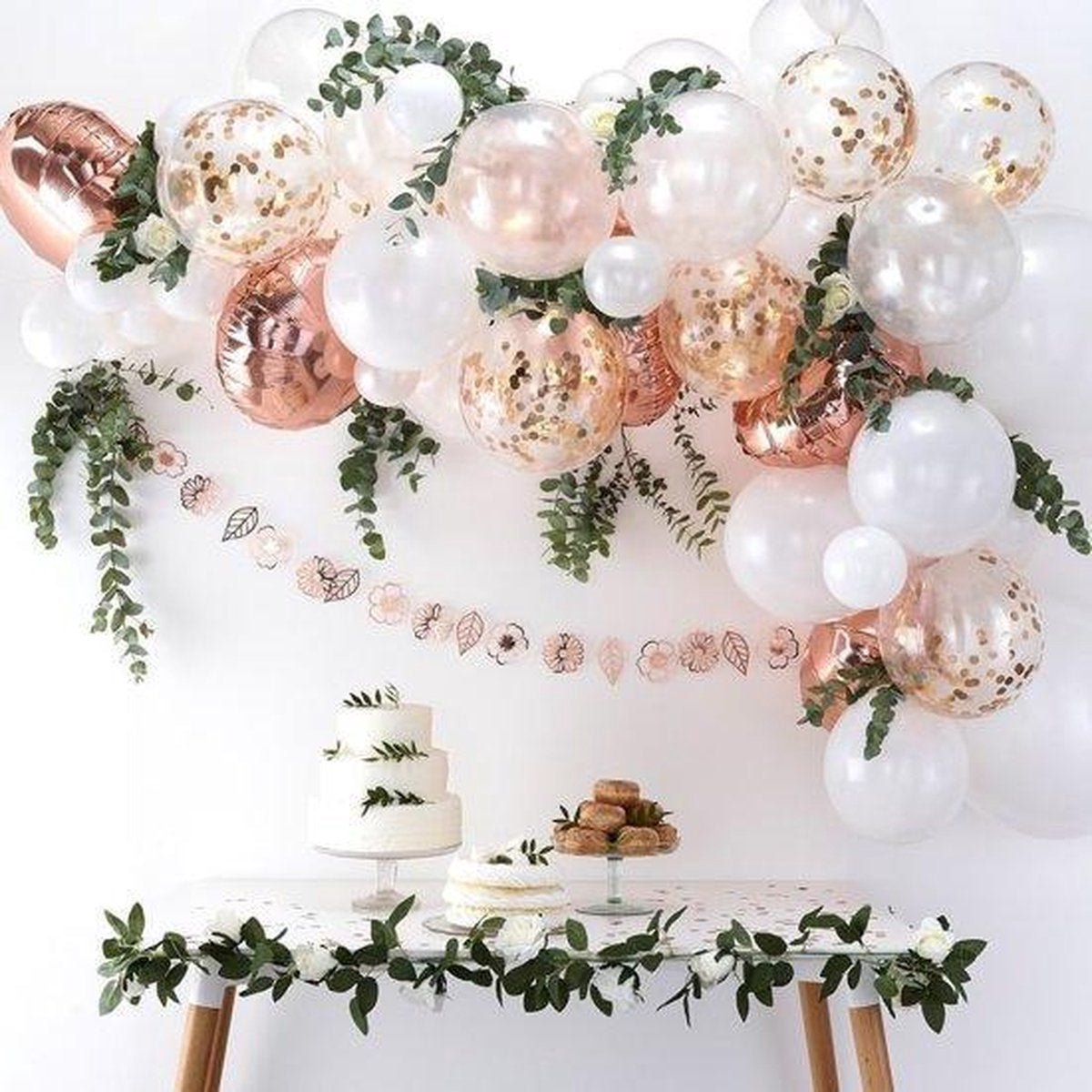 Decorative setup with balloons, cake, and greenery on a white background Main image