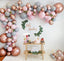 Balloon arch with pink, gray, and rose gold balloons, 'Oh Baby' sign, and dessert table.