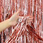 Hand holding rose gold tinsel curtain backdrop against a rose gold tinsel curtain