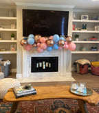 Decorative balloon arch in a living room with a fireplace and shelves.