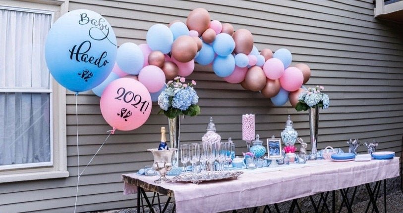 Decorated outdoor table with balloons and party supplies for a baby shower.