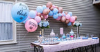 Decorated outdoor table with balloons and party supplies for a baby shower.