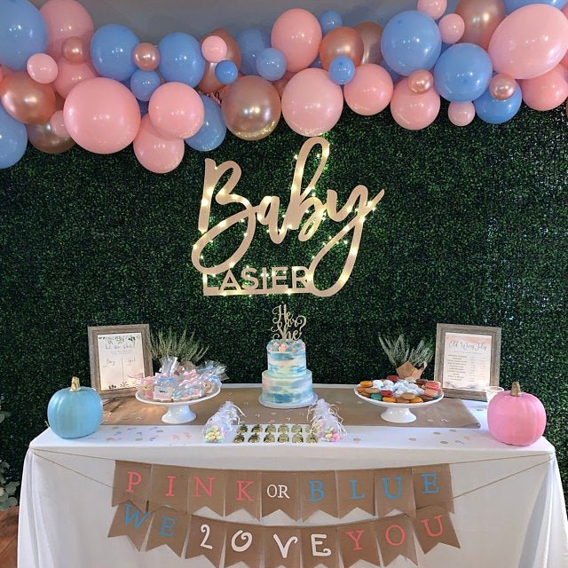 Baby shower setup with balloons, cake, and gender reveal banner.