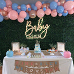 Baby shower setup with balloons, cake, and gender reveal banner.