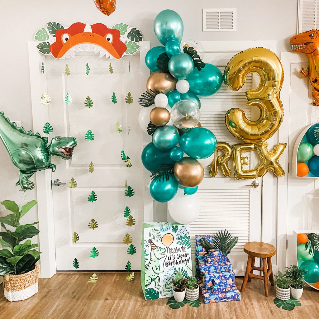 Dinosaur-themed birthday party setup with balloons, decorations, and a '3 Rex' sign.