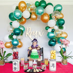 Decorative balloon arch with 'Roux' sign above a table with food and plants.