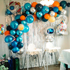 Decorative balloon arch with robot balloons and a silver tinsel curtain in a party setting.