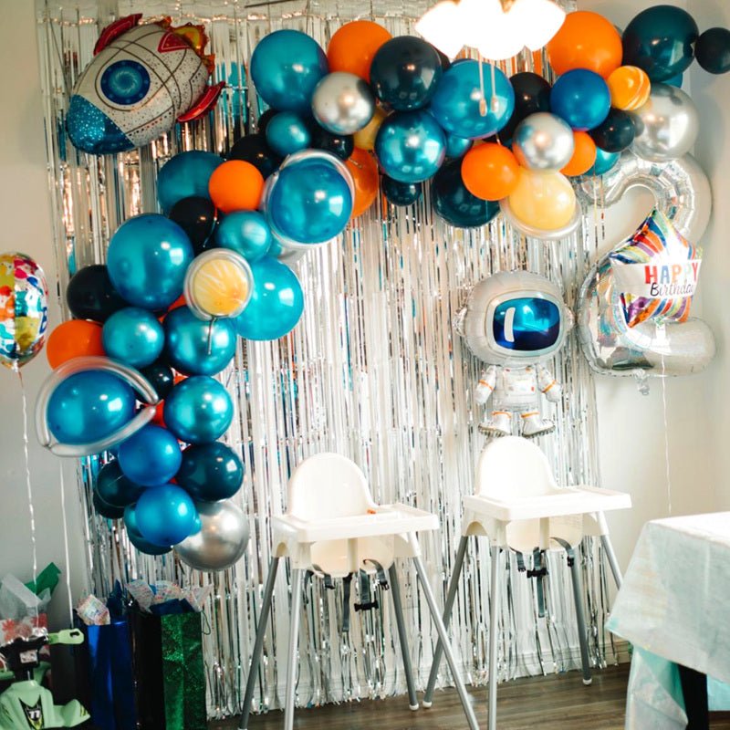 Decorative balloon arch with robot balloons and a silver tinsel curtain in a party setting.