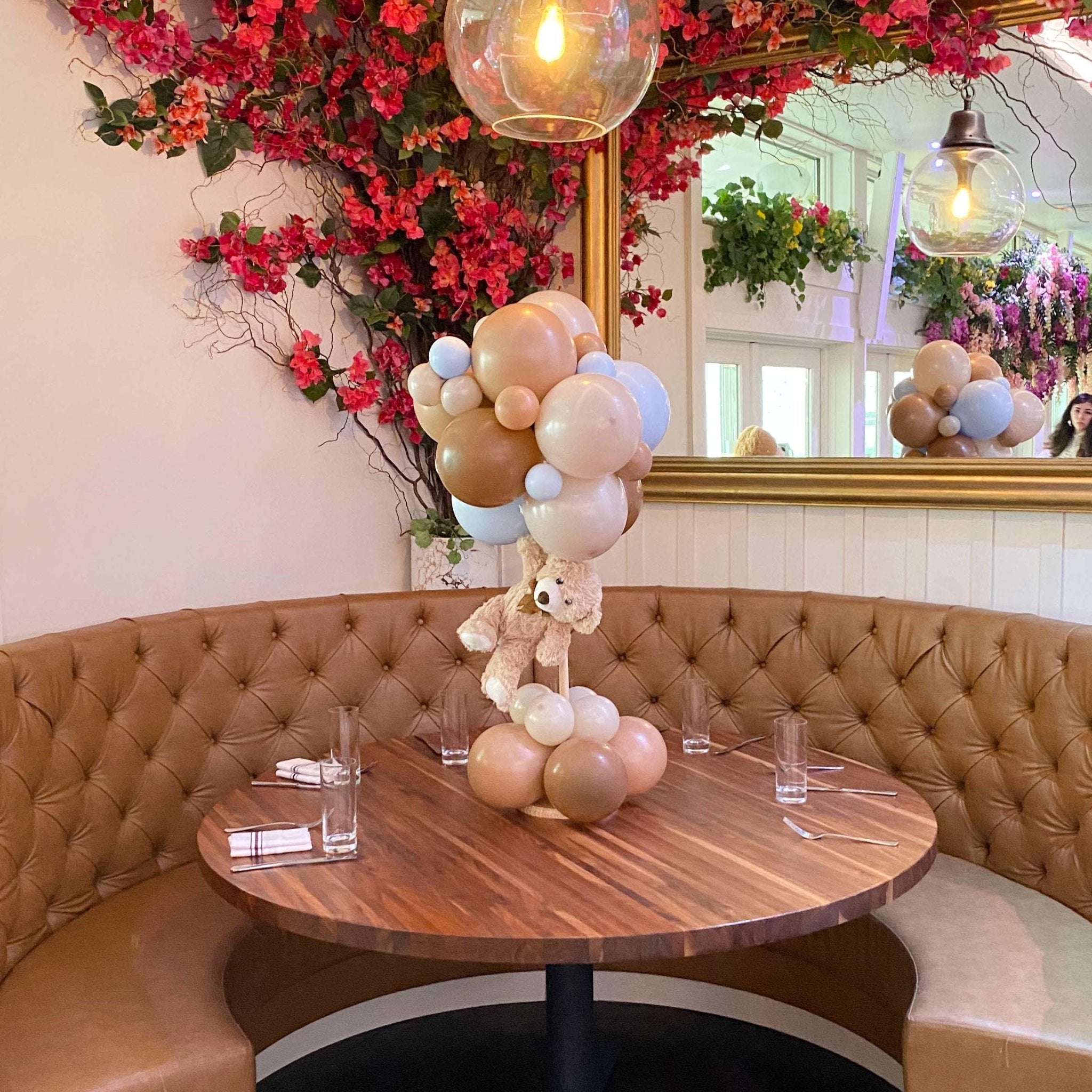 Decorative table with balloons and a teddy bear in a stylish interior setting.