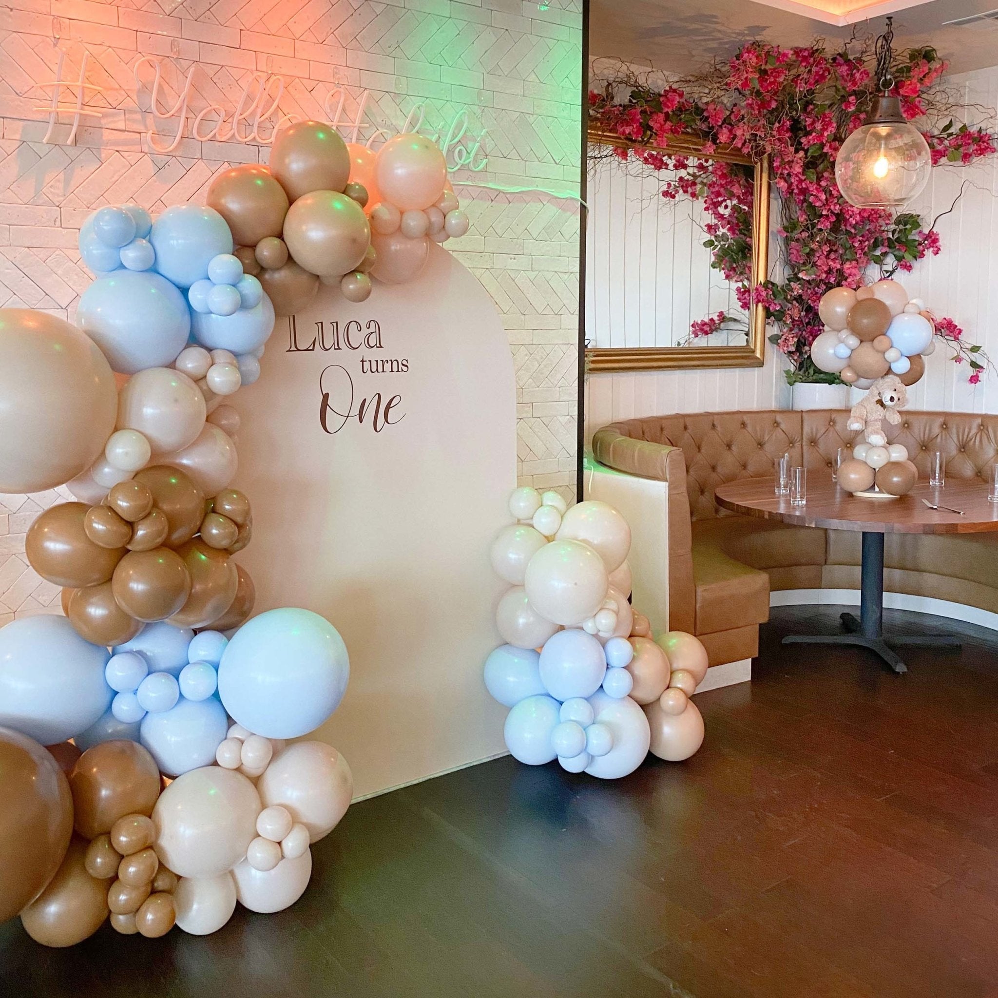 Balloon arches with pastel colors in a decorated room with flowers and a mirror.